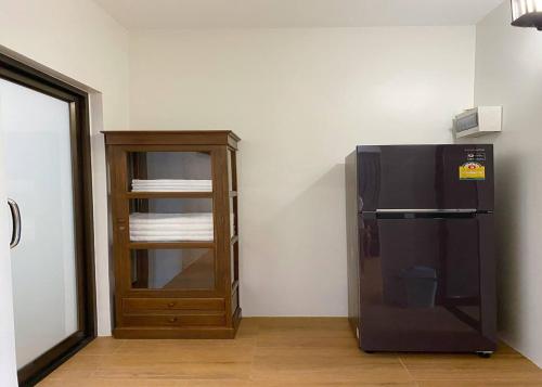 a black refrigerator next to a wooden cabinet at Sanaepatan Home Resort - เสน่ห์ป่าตาล โฮม รีสอร์ต in San Kamphaeng