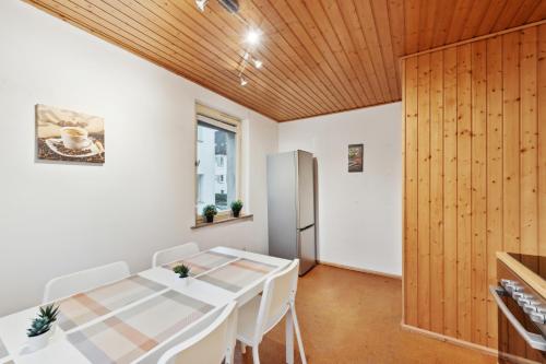 a dining room with a white table and a wooden ceiling at GÜNSTIGES Apartmenthaus für Monteure in Waiblingen City Wifi, Smart TV, Parking NEW in Waiblingen