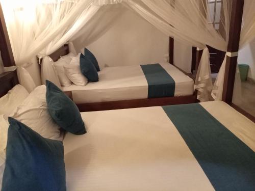 two beds in a small room with white and blue at Green Grove in Matara