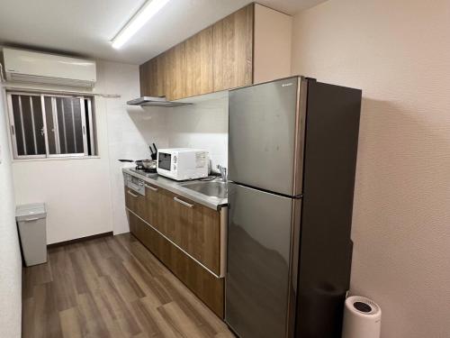 a kitchen with a stainless steel refrigerator and wooden cabinets at 环球影城附近安静独栋简约新风民宿 in Osaka