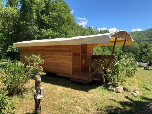 a wooden cabin with an umbrella on the grass at Camping RioRequesa in Campore
