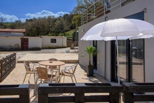 a patio with a table and chairs and an umbrella at Martas Dream - Near Beach Apartments in Daratso