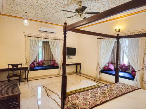 a bedroom with a canopy bed and two windows at The Amargarh in Udaipur