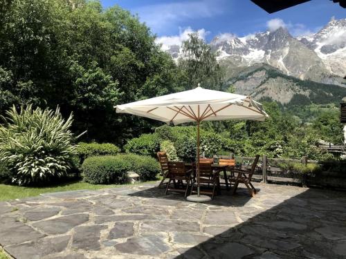 a table and chairs under an umbrella with mountains in the background at Splendido Alloggio con Giardino vista Monte Bianco in Courmayeur