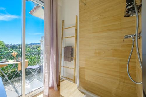 La salle de bains est pourvue d'une douche et d'une fenêtre avec vue. dans l'établissement LA GRANDE BLEUE, Magnifique T2 climatisé, proche de la mer, à Menton