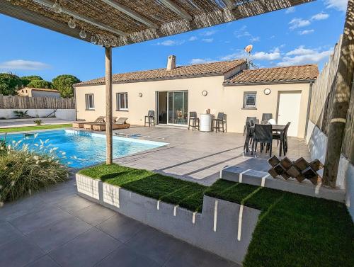 une cour arrière avec une piscine et une maison dans l'établissement Le point BE - Magnifique villa avec piscine chauffée - de mai à septembre - pour 6 personnes, à Ornaisons