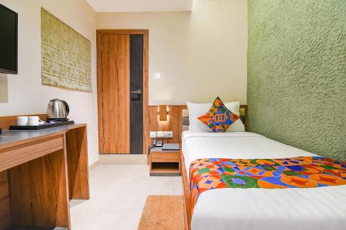 a bedroom with a bed and a desk with a television at FabHotel Prime Swagatam International Chinar Park in Kolkata