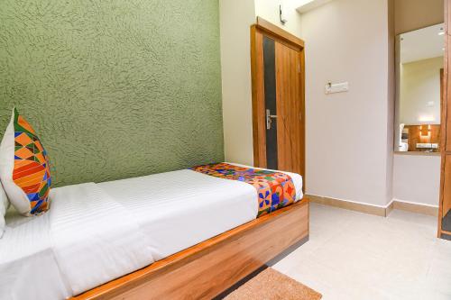 a bedroom with a bed and a green wall at FabHotel Prime Swagatam International Chinar Park in Kolkata