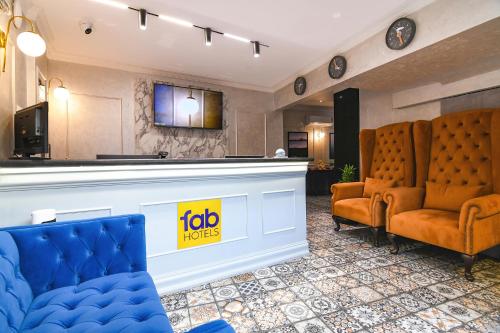 a hotel lobby with two chairs and a bar at FabHotel Prime Swagatam International Chinar Park in Kolkata