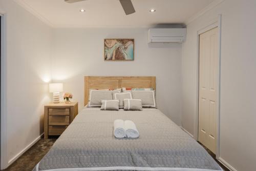 a bedroom with a bed with two white slippers on it at 123Chishlom in Wonthaggi