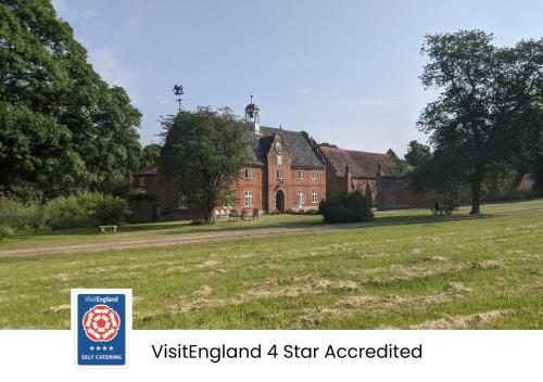 a large red brick house with a sign in front of it at Spixworth Hall Cottages in Spixworth