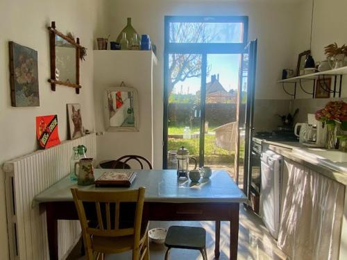 une cuisine avec une table et des chaises et une fenêtre dans l'établissement Maison de village, à Rémalard