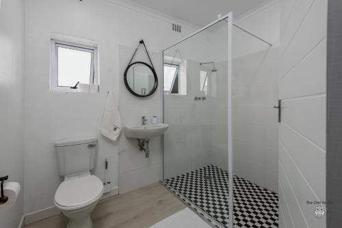 a white bathroom with a toilet and a sink at The Owl House Guest House in Port Elizabeth