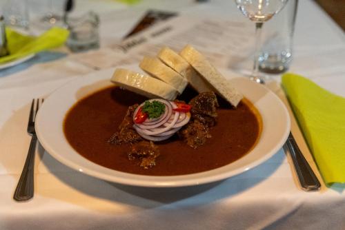a bowl of soup with cheese and crackers on a table at Hotel Rustikal Hustopeče - U Mandloňových sadů in Hustopeče