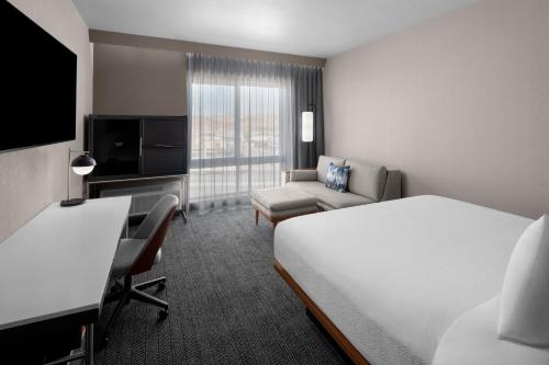 a hotel room with a bed and a couch and a tv at Courtyard by Marriott Reno Sparks in Clark