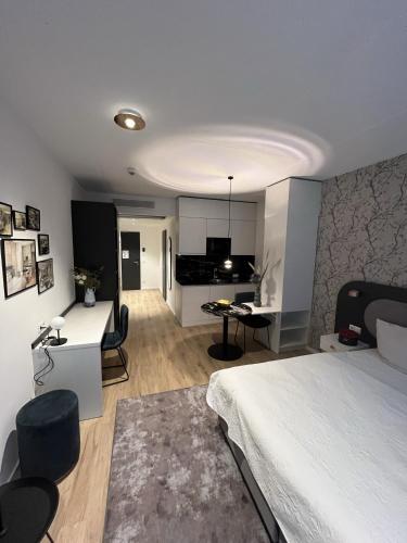 a bedroom with a white bed and a kitchen at MASEVEN Frankfurt Messe in Frankfurt/Main