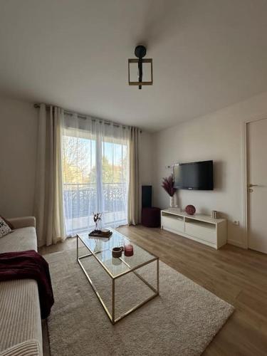 - un salon avec une table basse en verre et une télévision dans l'établissement Appartement Disney Val d'Europe, à Chessy