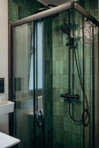 a shower in a bathroom with green tile at Zatoka Bielika Glamping in Sielsko