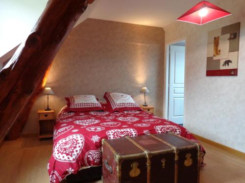 - une chambre avec un lit rouge et un coffre dans l'établissement La Boucle de l'Adour Chambres d'Hôtes, à Campan
