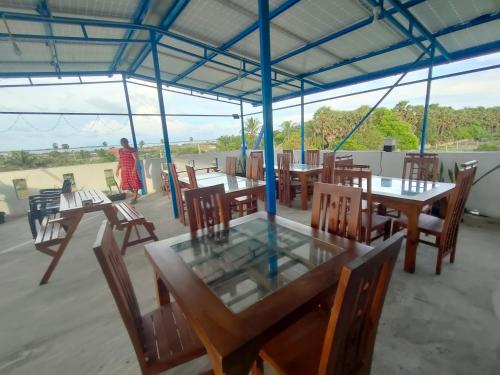a restaurant with wooden tables and chairs and a person at Victory's Gardens in Mannar