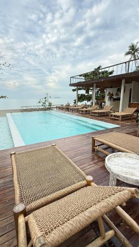 a resort with a pool with chairs and a table at Cape Beach Villa Samui in Ban Bang Po