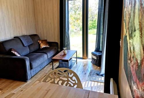 a living room with a couch and a table at Manège de la Chapinière - DadaLoge tiny-house in Châteauvieux