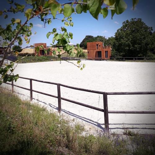 a fence in front of a field with a building at Manège de la Chapinière - DadaLoge tiny-house in Châteauvieux