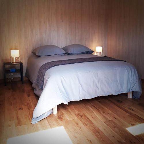 a bedroom with a large white bed with two lamps at Manège de la Chapinière - DadaLoge tiny-house in Châteauvieux