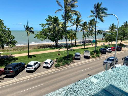 a street with parked cars and palm trees next to the beach at Watermark 105 in Townsville