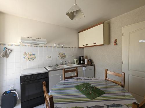 a kitchen with a table and a stove and a sink at Gîte paisible près de Valençay et Zoo de Beauval - FR-1-591-624 in Val-Fouzon