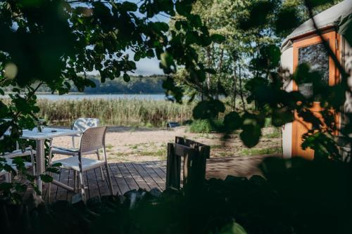 a table and chairs on a patio with a view of a lake at Zatoka Bielika Glamping in Sielsko