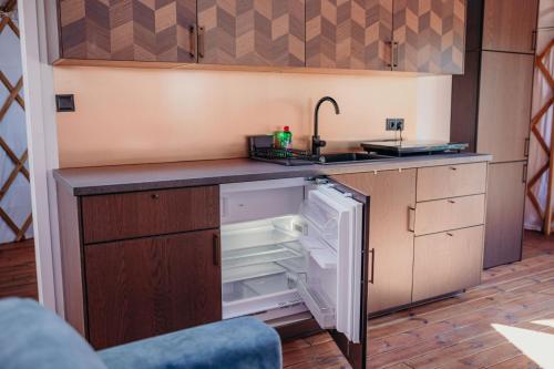 an empty kitchen with a sink and an open refrigerator at Zatoka Bielika Glamping in Sielsko