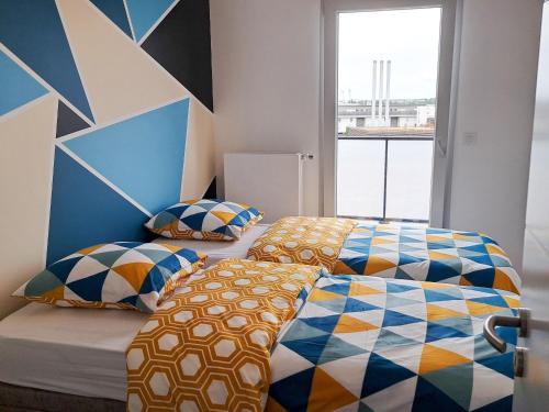 - une chambre avec 2 lits et un mur géométrique dans l'établissement Appartement contemporain 3 chambres avec vue sur canal, parking et internet à Nancy - FR-1-584-343, à Nancy