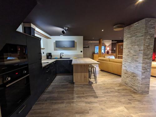 une cuisine avec des placards noirs, une table et un canapé dans l'établissement Chalet de charme pour 6 pers., proche ski, WiFi, parking, animaux admis - FR-1-589-683, à Cornimont