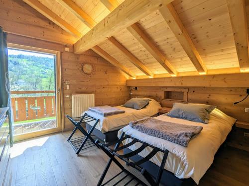 zwei Betten in einem Zimmer mit großem Fenster in der Unterkunft Chalet au cœur des Vosges avec sauna, terrasse et connexion WIFI - FR-1-589-692 in Cornimont