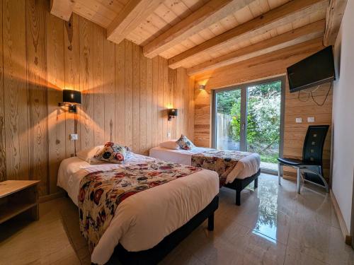 a bedroom with two beds in a room with wooden walls at Villa spacieuse avec spa et billard, WiFi, parking privé - FR-1-589-698 in Laveline