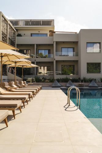 a hotel with a pool and chairs and umbrellas at Inea Sole Boutique Hotel in Kato Daratso