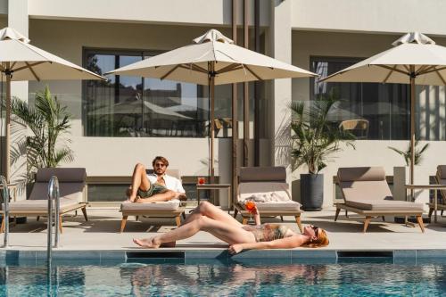 a woman laying on the edge of a swimming pool at Inea Sole Boutique Hotel in Kato Daratso