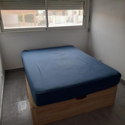 - un lit bleu dans une pièce avec fenêtre dans l'établissement Appartement à côté de la plage, au Barcarès