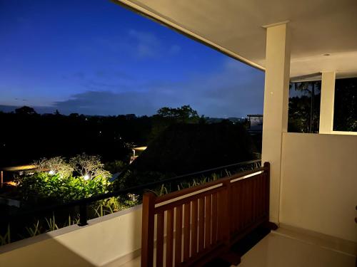 a balcony with a view of a garden at night at Brata Cottage Ubud in Ubud