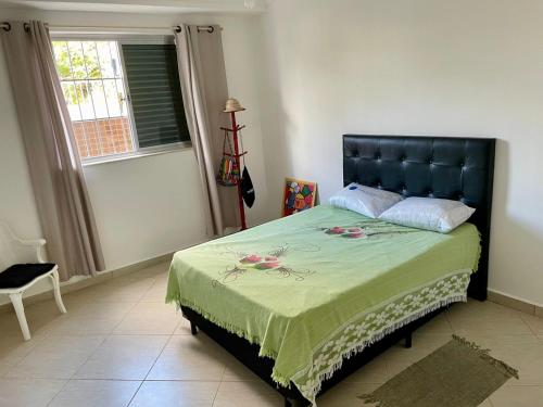 a bedroom with a bed with a green blanket and a window at Apartamento aconchegante no Centro de Peruibe in Peruíbe