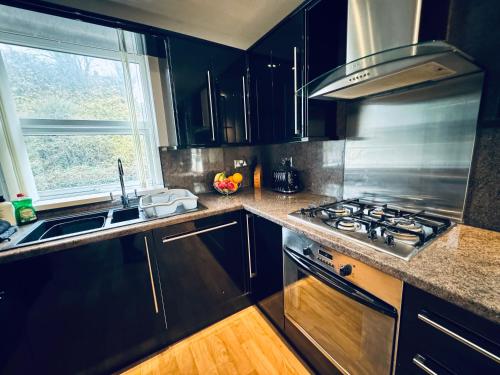 a kitchen with black cabinets and a stove and a window at New Road Apartment - 2 Bedrooms - Sleeps 3 in Whitehaven