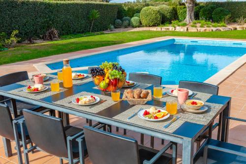 a table with plates of food next to a swimming pool at Villa Bliss by Algarve Vacation in Praia do Carvoeiro