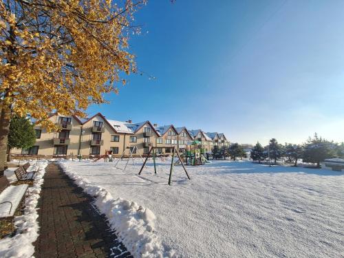 a playground in the snow in front of a building at Politechnika Warszawska Ośrodek Wypoczynkowy in Sarbinowo