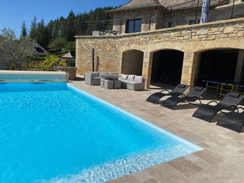 une piscine avec des chaises et une maison dans l'établissement Superbe Villa vue panoramique et piscine exterieure chauffée, à Saint-Côme-dʼOlt