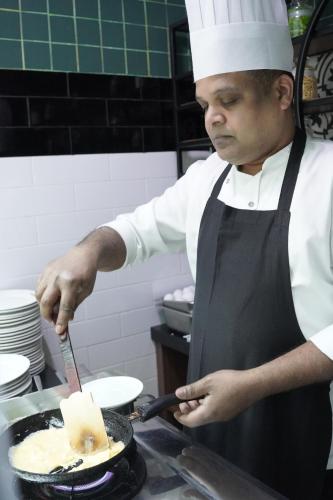 a man in a kitchen preparing food in a pan at FORTUNE ATRIUM HOTEL in Dubai