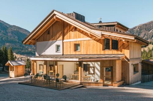 a wooden house with chairs and tables in front of it at La Lum De Roisc in Soraga