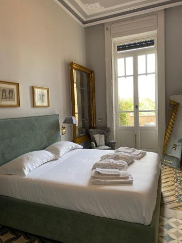a bedroom with a bed with white sheets and a window at Vittoria - house of charme in Messina
