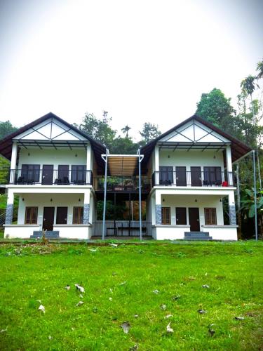 a large building with a green field in front of it at Caffeine Villa in Kaniyāmbetta