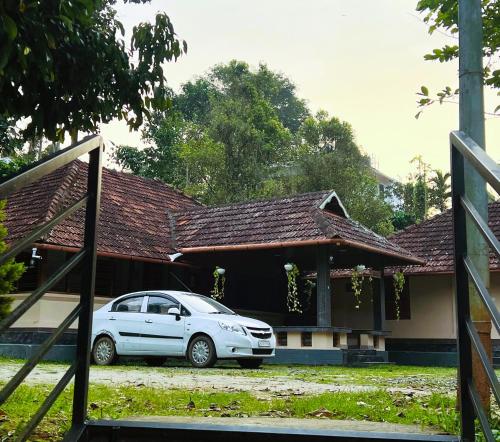 a white car parked in front of a house at Caffeine Villa in Kaniyāmbetta